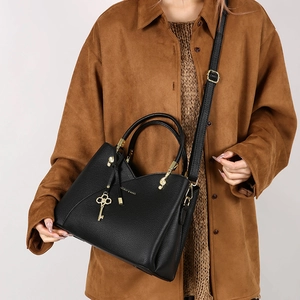 Detail of black lychee grain leather bucket bag with gold hardware and key charms