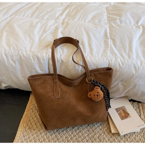 Détail du sac cabas marron en daim avec coutures blanches contrastées et porte-clés ours