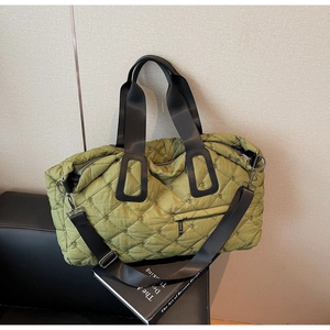Detail of green quilted puffer bag with rhombic stitching and black woven straps