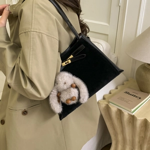 Detail of black leather handbag with gold metal twist lock and cute plush rabbit charm