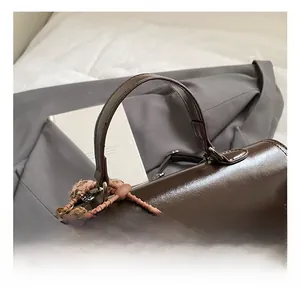Detail view of smooth brown faux leather handle with stylish charms and tassels