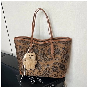 Close-up of vintage paisley pattern on brown tote bag with a cute teddy bear charm