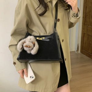 Detail of black leather handbag with velvet panel and a cute grey rabbit charm