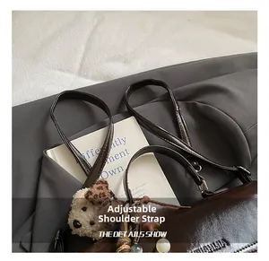 Detail of dark brown leather backpack with adjustable strap and decorative charm