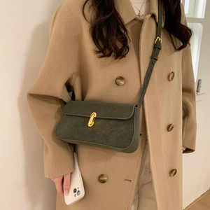 Detail of dark green suede-texture shoulder bag with a stylish gold metal buckle closure