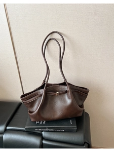 Détail d'un sac cabas marron foncé en similicuir avec fines lanières et boucle dorée