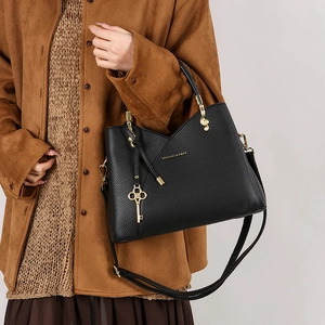 Detail of black textured bucket bag with gold key charm and musical hardware accents