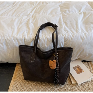 Détail du grand sac cabas marron mat avec coutures contrastées et breloque ours sur tapis