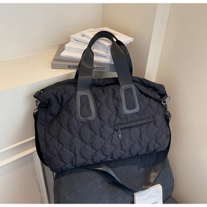 Close-up of quilted black nylon tote bag with embroidery on a stylish armchair