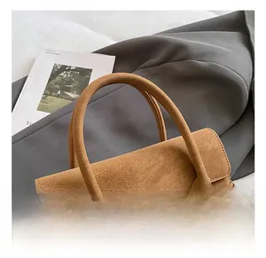 Dettaglio di borsa scamosciata marrone con fibbia in metallo dorato e cinturini in pelle laterali