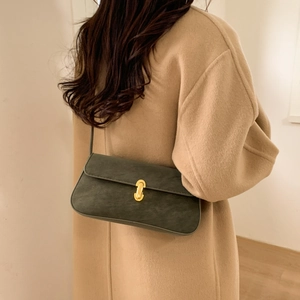 Detail of dark green matte leather underarm bag with gold metal U-shaped lock on coat