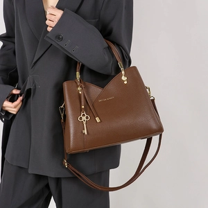 Detail of dark brown lychee leather bucket bag with gold key and music note pendants