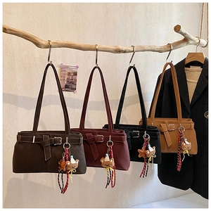 Artistic display of matte leather tote bags with bear charms on wooden branches