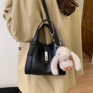 Detail of black pebble leather bucket bag with silver lock and plush bunny charm
