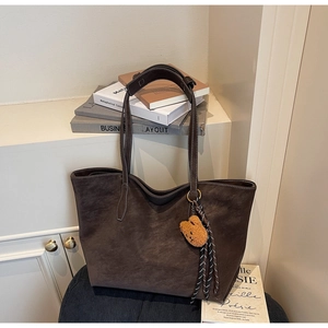 Détail macro du sac cabas en daim marron avec surpiqûres et breloque ourson