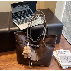 Close-up of vintage dark brown tote bag with decorative straps and plush puppy charm