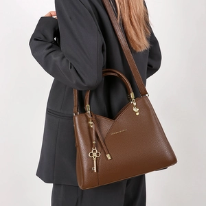 Detail of vintage dark brown bucket bag with lychee texture and golden key charm