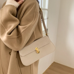 Chic cream baguette bag with gold buckle styled on a wool coat for a trendy winter look