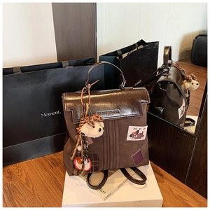 Détail d'un sac à dos vintage marron avec écussons de dessin animé et pendentif chien