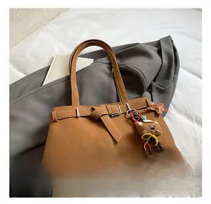 Close-up of vintage brown shoulder bag with metal buckle and plush bear charm decoration