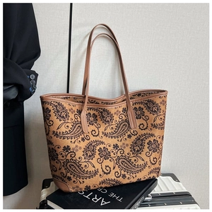 Detail of vintage paisley print tote bag with brown leather handles on art books