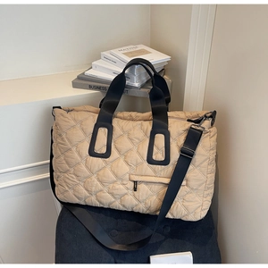Macro detail of quilted down tote bag with floral embroidery and wide strap on a velvet seat