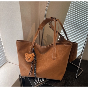Détails du sac fourre-tout marron mat montrant des coutures fines et un charm d'ours mignon