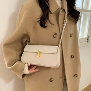 Detail shot of a cream leather underarm bag with an elegant gold metal twist lock