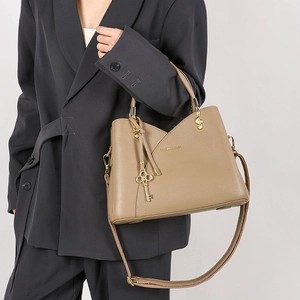 Detail of khaki leather bucket bag featuring gold musical charms and V-cut design