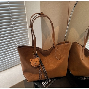 Détail d'un grand sac cabas en daim marron avec pendentif ours en peluche et ruban