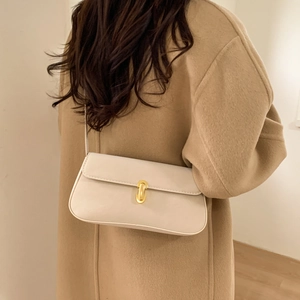 Minimalist beige leather shoulder bag with gold clasp shown on a wool coat