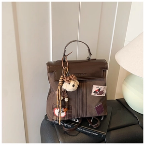 Detail of dark brown backpack with decorative patches and cute plush bear accessory