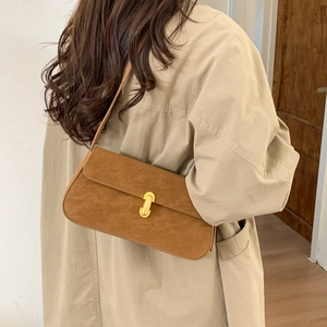 Brown faux suede underarm bag with gold metal lock buckle on a beige trench coat