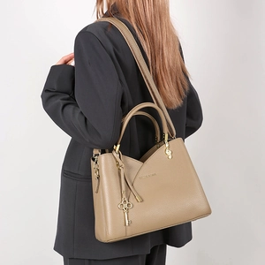 Detail of khaki litchi grain leather bag with vintage key and music note charms