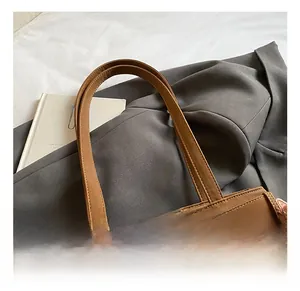 Detail of brown leather tote bag featuring lychee texture and silver buckle accents