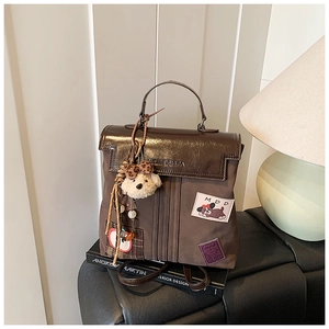 Detail of vintage brown backpack featuring cartoon patch and plush bear charm decoration