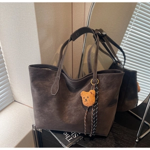 Détail du sac cabas en daim marron foncé avec pendentif ours en peluche et charme tressé