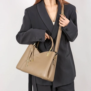 Detail of khaki bucket bag with lychee texture, golden key charm, and logo embossing