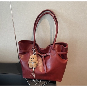 Detail view of burgundy tote bag with fine matte texture and plush puppy charm