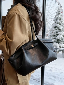 Grand sac cabas noir en similicuir avec détails dorés dans un décor hivernal enneigé