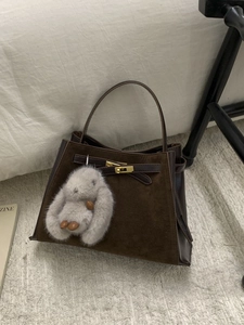 Retro contrast stitching brown bucket bag with plush rabbit pendant on white carpet