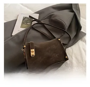 Detail view of dark brown vintage shoulder bag with gold hardware on a grey blazer