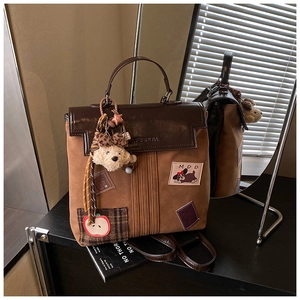 Détail du sac à dos en cuir marron avec écusson chien et breloque en peluche