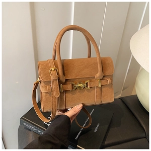 Detail of vintage brown crossbody bag with gold heart-shaped metal buckle and matte leather texture