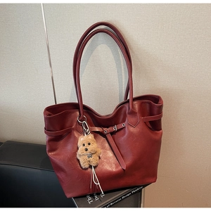 Detailed texture of dark red large tote bag with plush puppy pendant and metal buckle