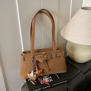 Detail of tan faux leather shoulder bag with decorative strap buckle and plush bear charm