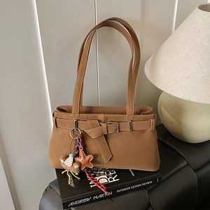 Detail of vintage brown suede shoulder bag with decorative belt strap and plush bear charm
