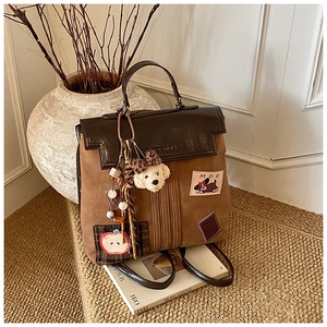 Detail of vintage brown suede backpack featuring cute puppy patch and plush pendant charm