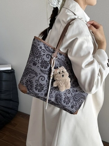 Retro paisley tote bag in grey fabric with brown leather straps shown on a model