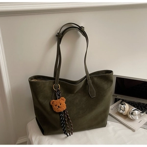 Détail du grand sac cabas vert foncé mat avec pendentif ours et coutures fines